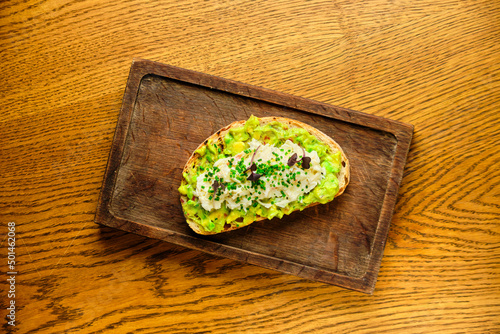 Whole grain bread toast with avocado on a wooden board