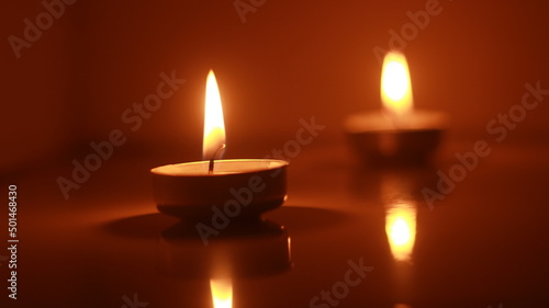 Two candles light burning brightly in the black background.