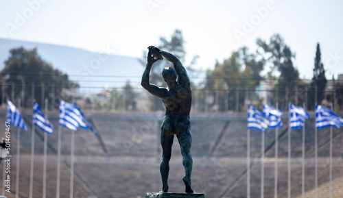 Athens, Greece. Discus thrower bronze statue, rear view. Panathenaic Stadium blur background photo