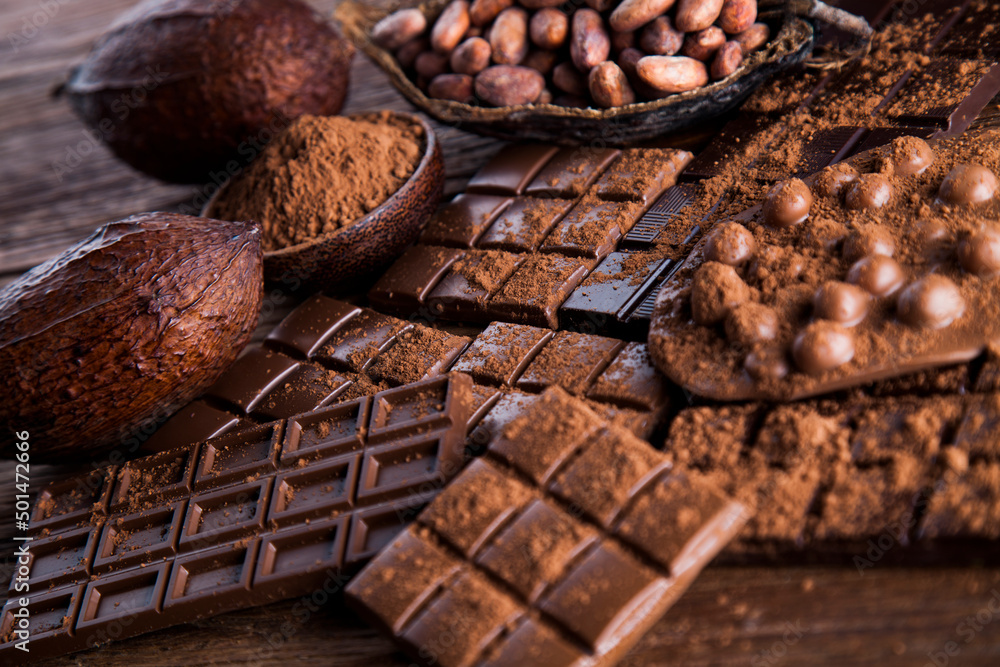 Dark homemade chocolate bars and cocoa pod on wooden Dark homemade chocolate bars and cocoa pod on wooden
