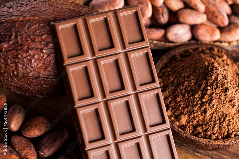 Chocolate bar, candy sweet, cacao beans and powder on wooden background Chocolate bar, candy sweet, cacao beans and powder on wooden background