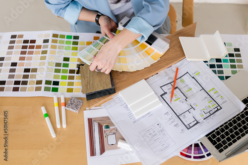 Designer choosing color samples according to the visualization and blueprints of the project. Woman architect working on interior renovation in workplace. Architecture and interior design concept.
