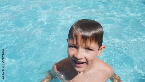 Caucasian boy emerges from pool water, happy kid looking into camera. summer Concept