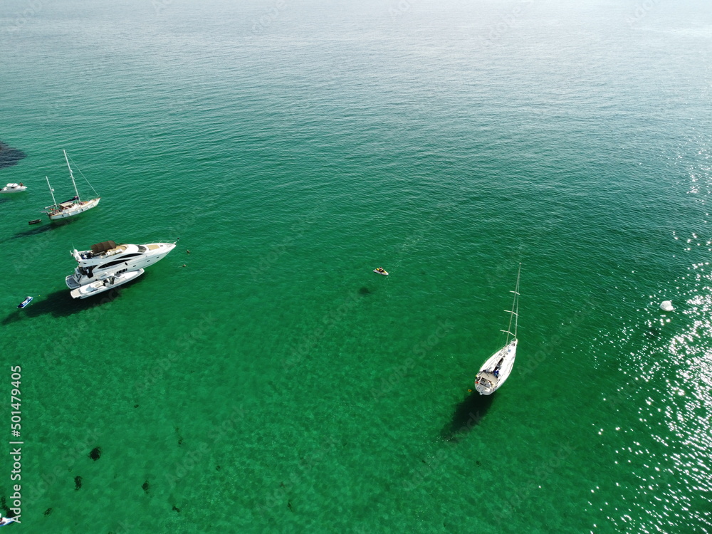 Aerial panoramic view of seascape with crystal clear azure sea and rocky shores. Yachts in a beautiful lagoon on backdrop of rocks. The concept of an ideal destination for summer travel and vacation.