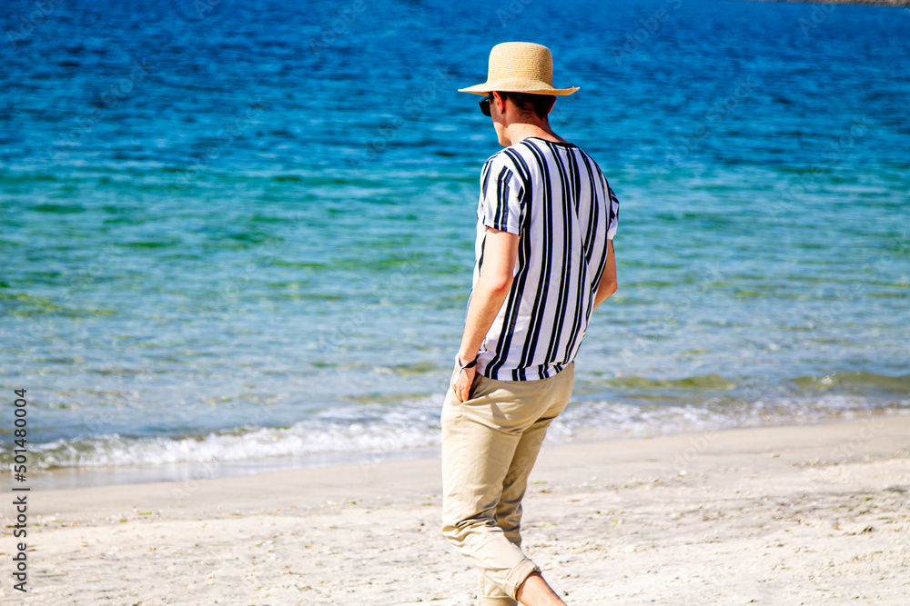 young man walking along the shore of the beach