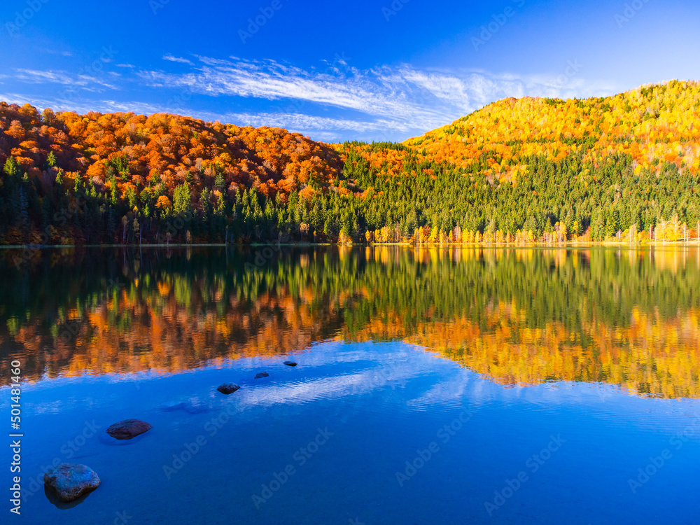 Idyllischer Bergsee umgeben von buntem Herbstwald