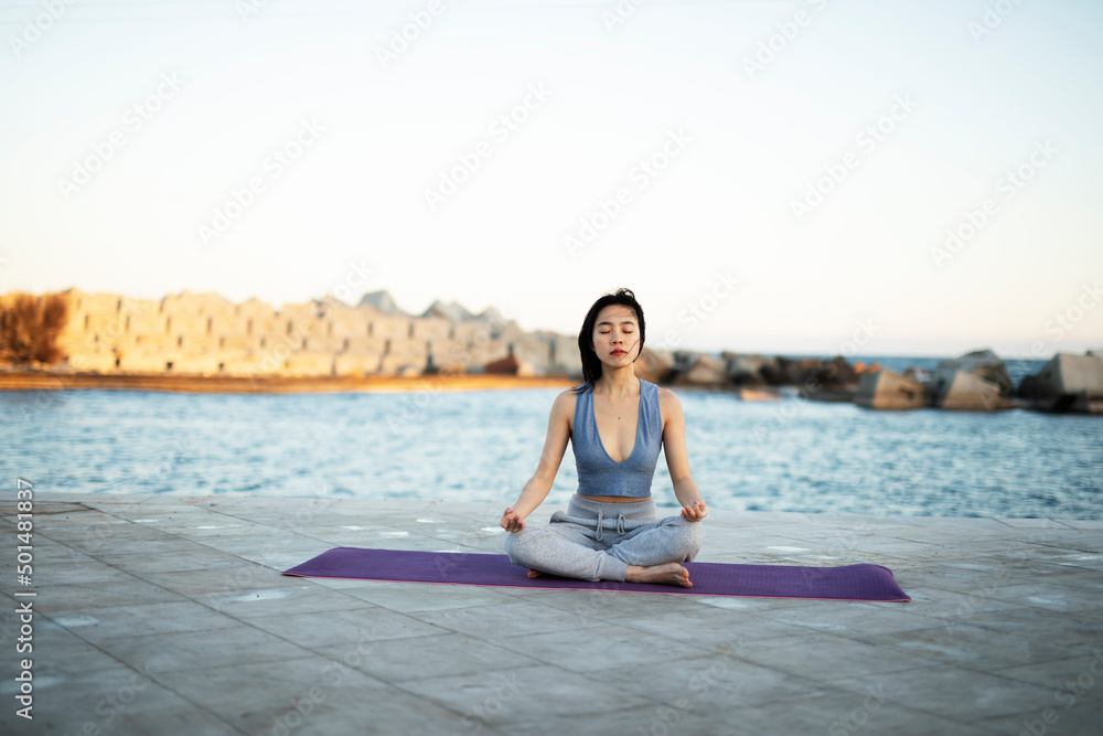 Beautiful young woman stretching outside. Fit woman doing yoga exercise