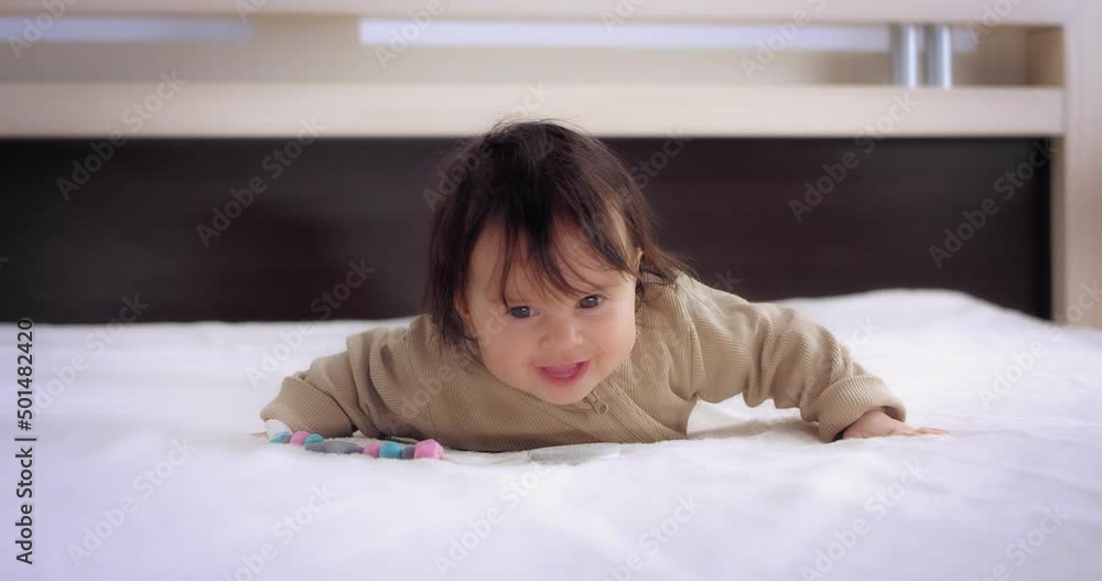 Funny baby girl in a sand bodysuit is lying on her stomach on a white