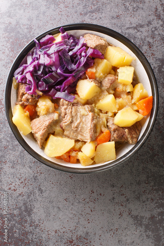 Scouse is a slow lamb stew with potatoes, turnips, onions and carrots close-up in a plate on the table. Vertical top view from above