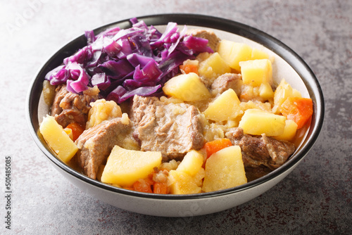 Scouse is a stew with meat and vegetables served with pickled cabbage close-up in a plate on the table. Horizontal