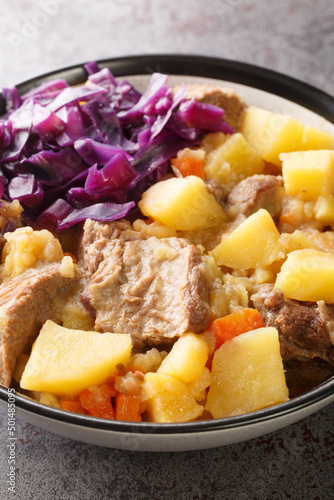 Scouse is a slow lamb stew with potatoes, turnips, onions and carrots close-up in a plate on the table. Vertical