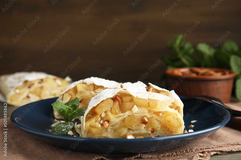 Delicious apple strudel with almonds, powdered sugar and mint on table, closeup. Space for text Delicious apple strudel with almonds, powdered sugar and mint on table, closeup. Space for text