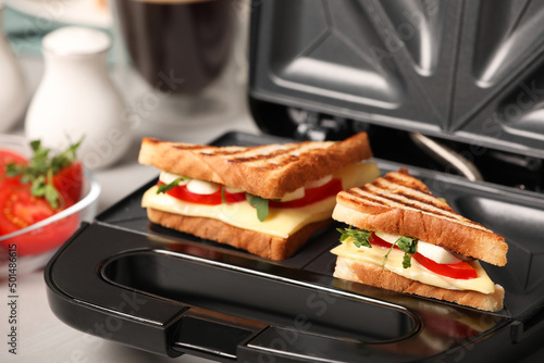Modern grill maker with sandwiches on table, closeup view