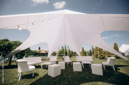 banquet table setting under a white tent on the grass
