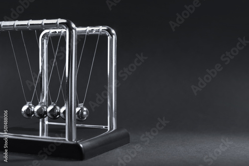 Newton's cradle on dark background, space for text. Physics law of energy conservation