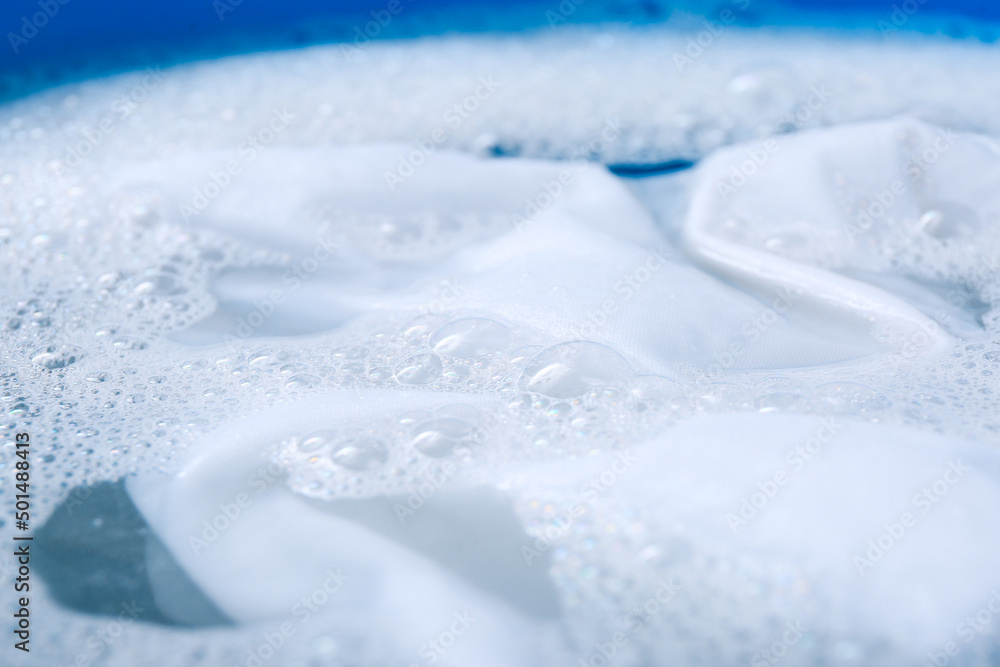 White garment in suds, closeup. Hand washing laundry White garment in suds, closeup. Hand washing laundry