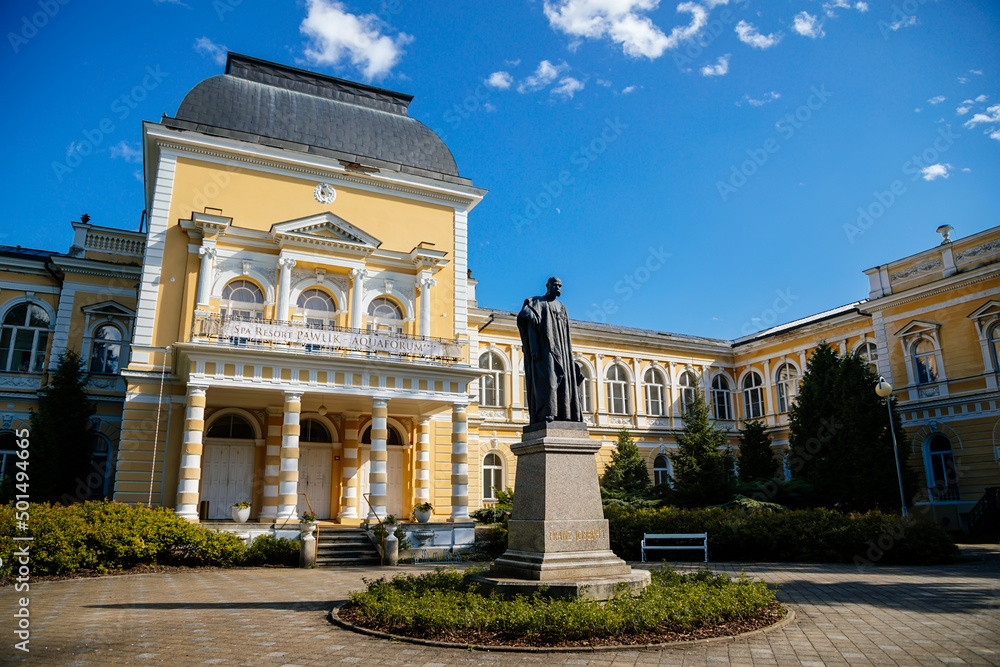 Obraz premium Frantiskovy Lazne, Western Bohemia, Czech Republic, 14 August 2021: Neo-Renaissance building Imperial Baths in park of great famous spa town Franzensbad, Monument to Francis Joseph I, sunny day