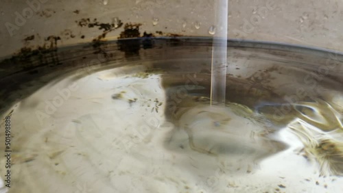 Macro closeup of drop of water leaking from pipe inside bucket, costant ripples photo