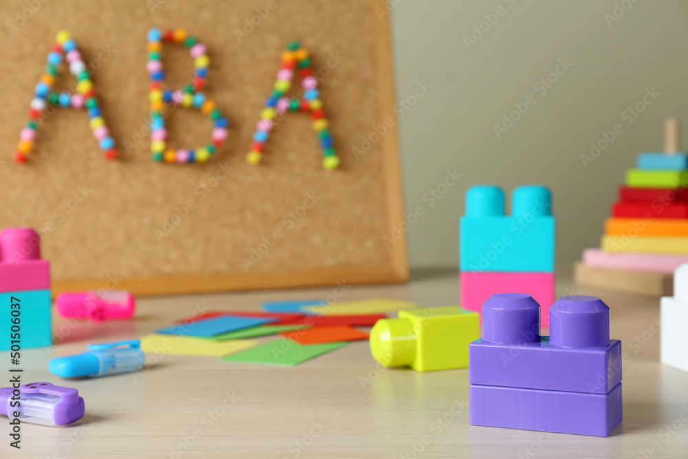 Cork board with abbreviation ABA (Applied behavior analysis) at table, focus on colorful blocks Cork board with abbreviation ABA (Applied behavior analysis) at table, focus on colorful blocks