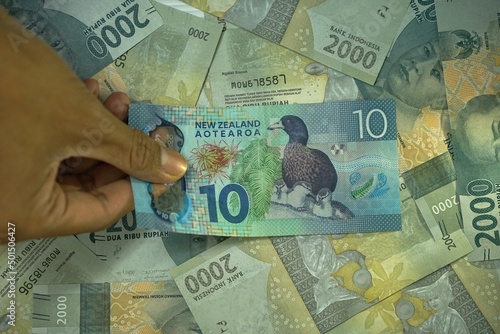 10 NZD, Ten New Zealand dollar concept, was held by businessman on money background photo