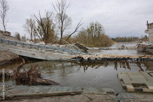 Damaged bridge across the river. The civilian object was blown up. War in Ukraine. Destroyed infrastructure. Broken communications. Humanitarian catastrophe.