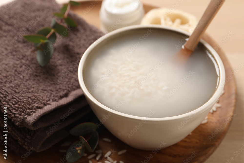 Bowl with soaked rice and spoon near towel on wooden tray, closeup Bowl with soaked rice and spoon near towel on wooden tray, closeup