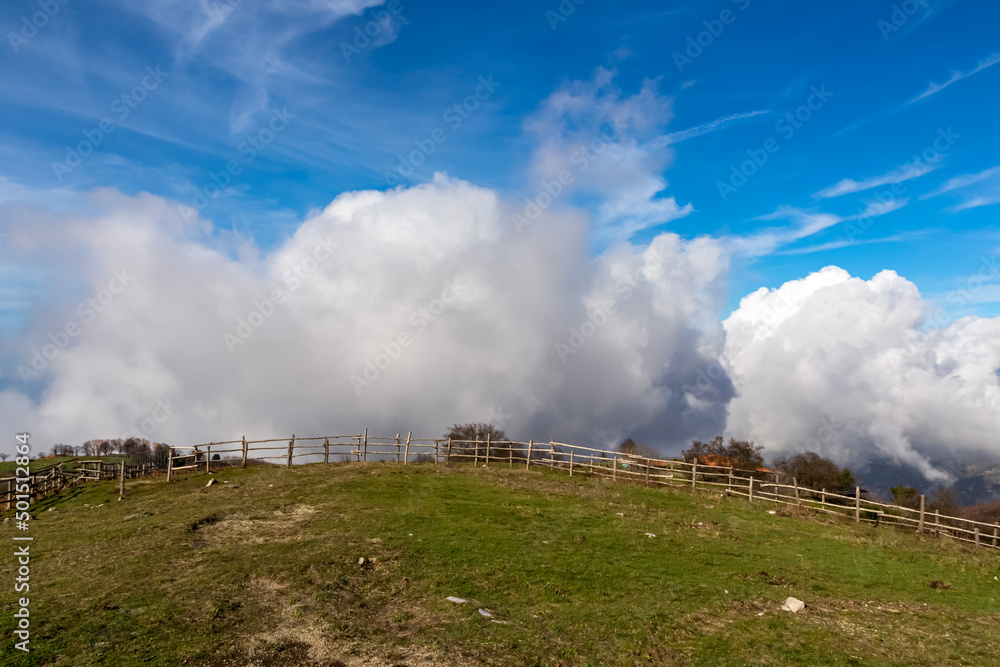 Thick clouds accumulating over the summit of Monte Comune, Lattari Mountains, Apennines, Amalfi Coast, Campania, Italy. Hiking trail near the coastal town Positano. Alpine lush green pasture meadow