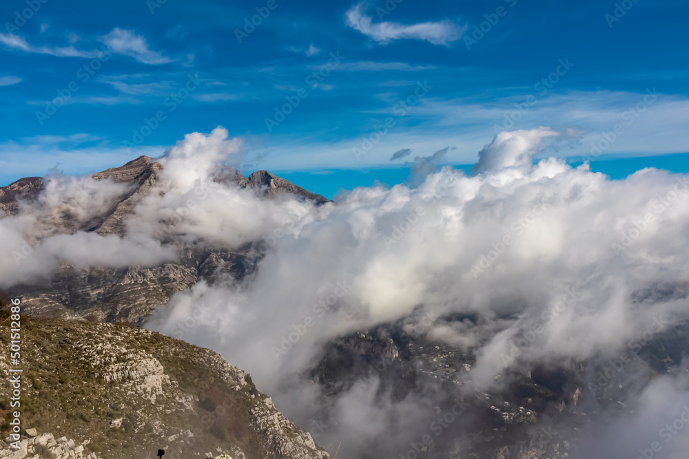 Obraz premium Panoramic view from Monte Comune on cloud covered peaks of Monte Molare, Canino, Caldare in Lattari Mountains, Apennines, Amalfi Coast, Italy, Europe. Hiking trail near the coastal town Positano.