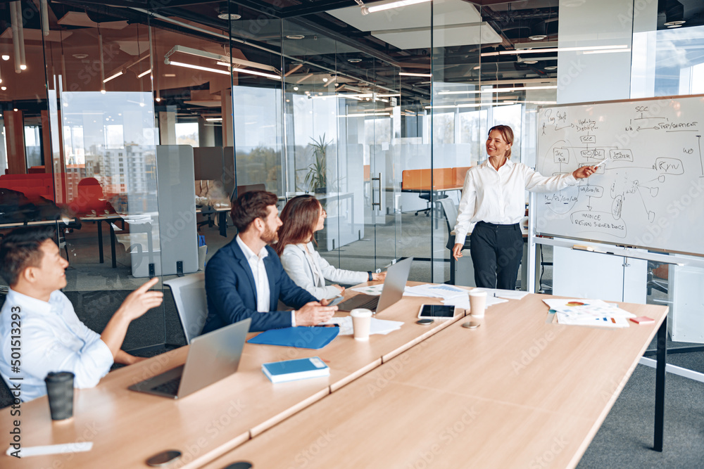 Skilled mature caucasian leader coaching interested business people, giving presentation in office.