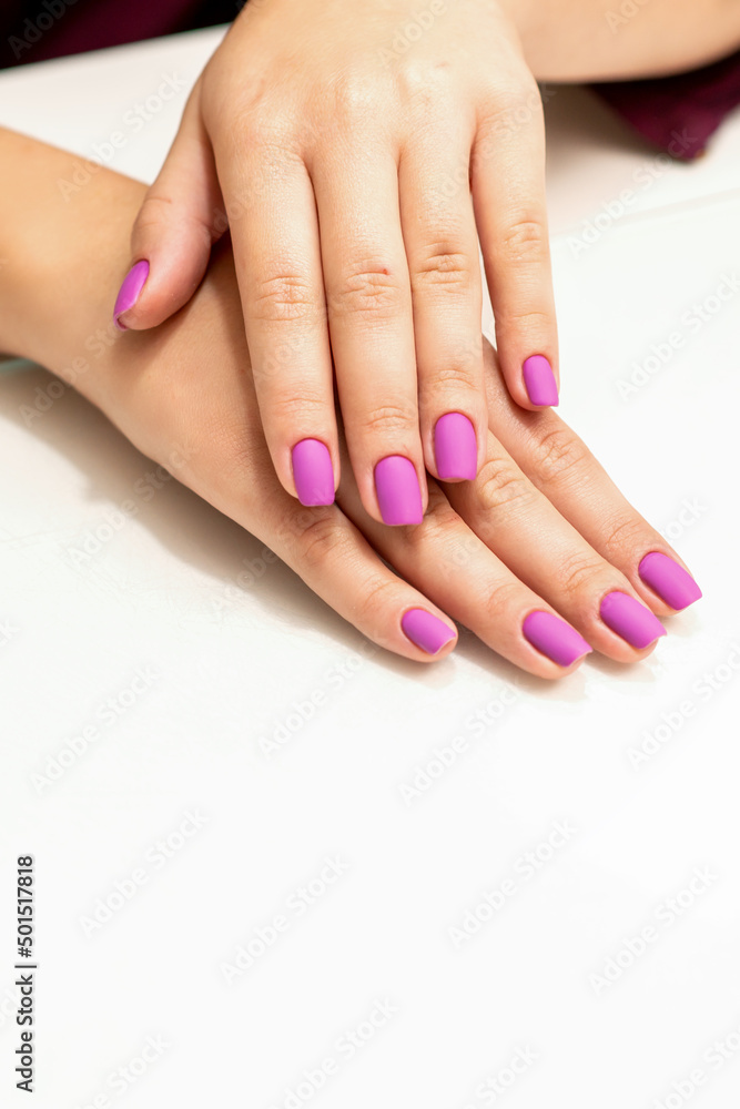 Beautiful manicure with purple, pink nail polish on young caucasian female hands Beautiful manicure with purple, pink nail polish on young caucasian female hands