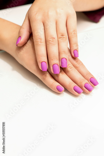 Beautiful manicure with purple  pink nail polish on young caucasian female hands