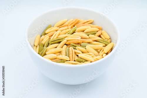 Closeup of colorful raw malloreddus pasta in a bowl on a white surface photo
