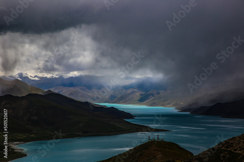 Mesmerizing view of Yamdrok Yongcuo lake surrounded by mountains over cloudy sky in Tibet, China photo