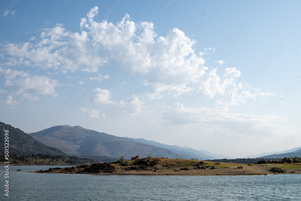 Beautiful landscape of a lake with a background of mountains and clouds.