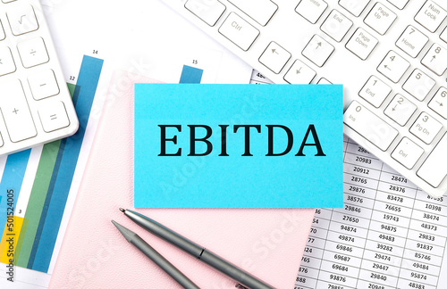 EBITDA text on blue sticker on chart with calculator and keyboard,Business concept
