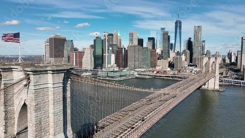 aerial moving lateral across American flag Brooklyn Bridge Manhattan skyline New York City