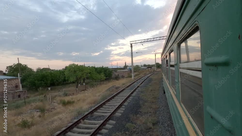 Passenger train. View from a driving passenger train. Old style train driving  early in the morning.  Person traveling in Armenia, Caucasus. View on other  train tracks and village.