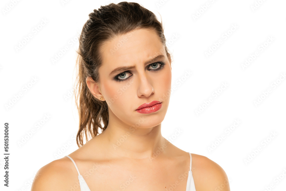 Beautiful unhappy woman with make up and tied hair on a white background Beautiful unhappy woman with make up and tied hair on a white background