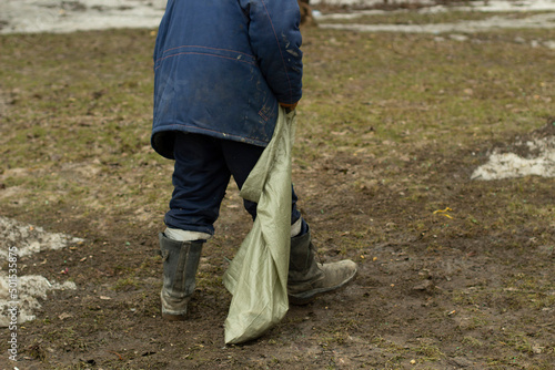 Garbage collection in a bag. The cleaner collects plastic debris from the lawn. A utility employee cleans up the mess. photo