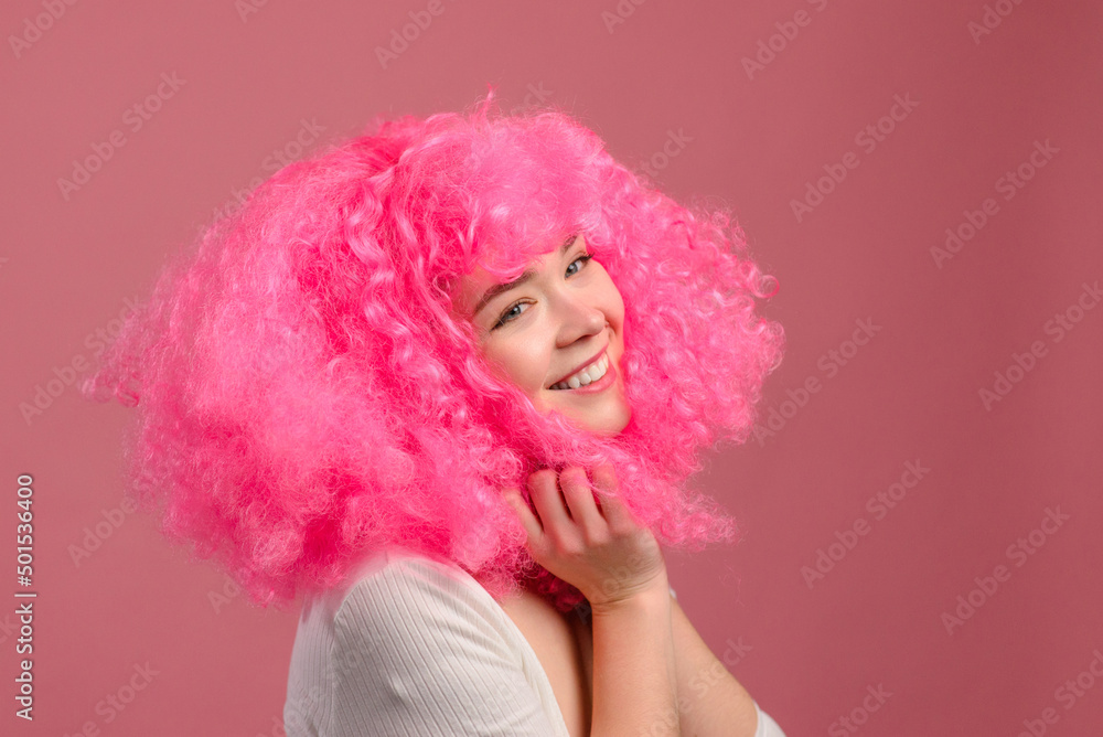 Smiling young pink haired woman on pink background. Funny close-up portrait. Smiling young pink haired woman on pink background. Funny close-up portrait.