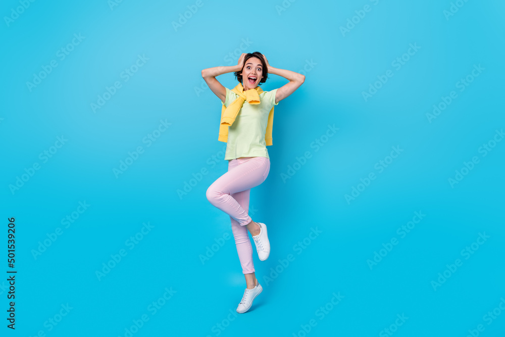 Full body photo of cool young brunette lady jump look camera wear t-shirt pants sneakers isolated on blue background Full body photo of cool young brunette lady jump look camera wear t-shirt pants sneakers isolated on blue background