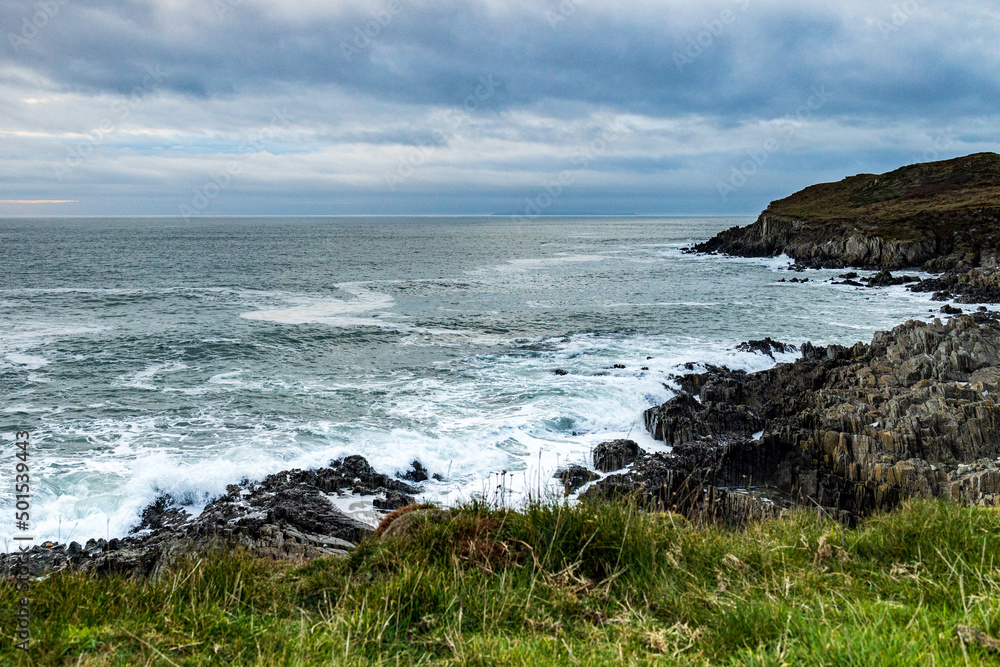 From a green headland, looking across a rocky cove on a cold November day, with a dramatic sky. From a green headland, looking across a rocky cove on a cold November day, with a dramatic sky.