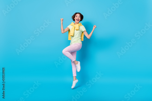 Fototapeta Naklejka Na Ścianę i Meble -  Full size photo of celebrate millennial brunette lady jump yell wear t-shirt pants shoes isolated on blue background