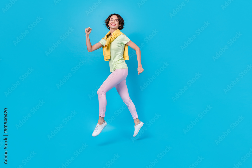 Full size profile photo of cool young brunette lady run wear t-shirt trousers shoes isolated on blue background