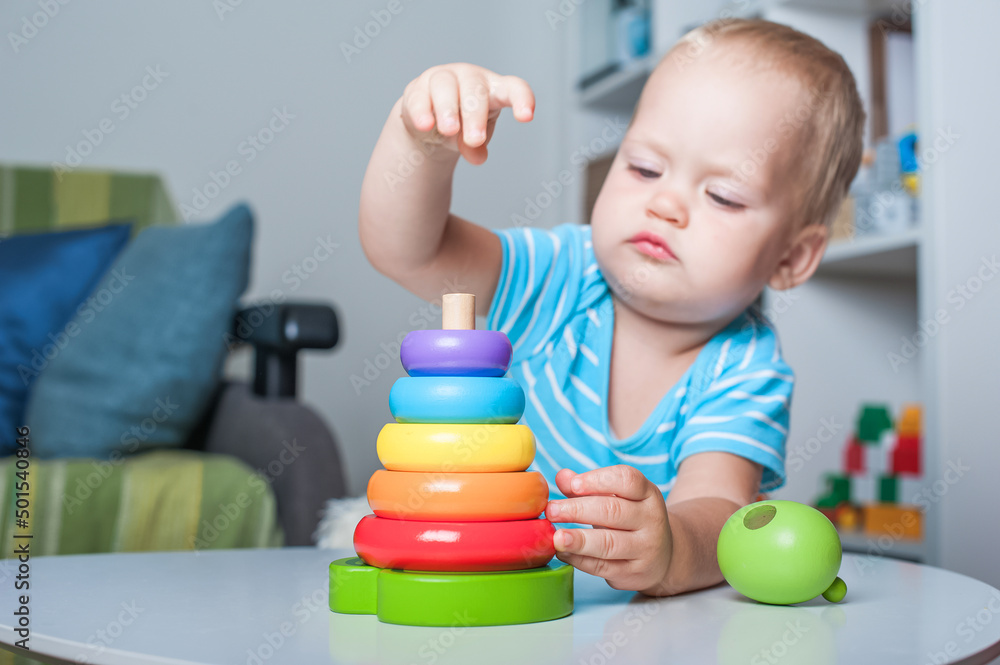 Handsome toddler boy playing with educational wooden and plastic toys in children's room.. Handsome toddler boy playing with educational wooden and plastic toys in children's room..