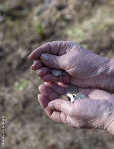 A pensioner woman counts small money in her hands.