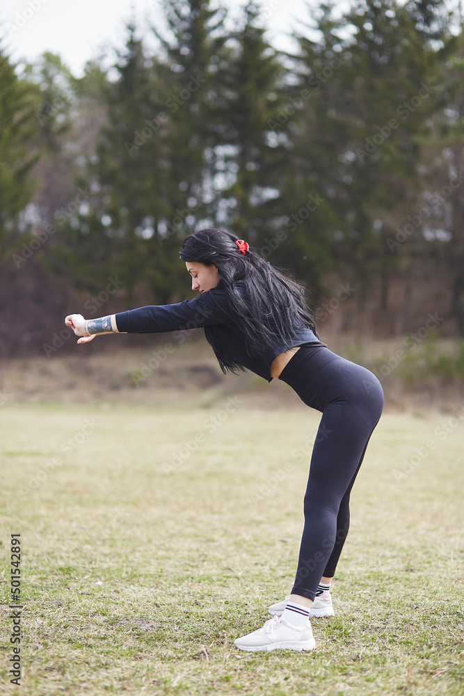 Young slim woman doing exercises outside in front of the forest. Wellness, wellbeing, healthy lifestyle. Fresh air, cottagecore aesthetic. Active, athletic girl working out in spring day Young slim woman doing exercises outside in front of the forest. Wellness, wellbeing, healthy lifestyle. Fresh air, cottagecore aesthetic. Active, athletic girl working out in spring day