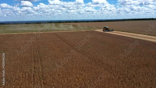 Combine harvester in a soybean field on farmland deforested in the Brazilian cerrado - aerial flyover photo