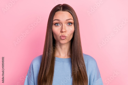 Portrait of attractive amorous brunet girl sending air kiss isolated over pink pastel color background © deagreez
