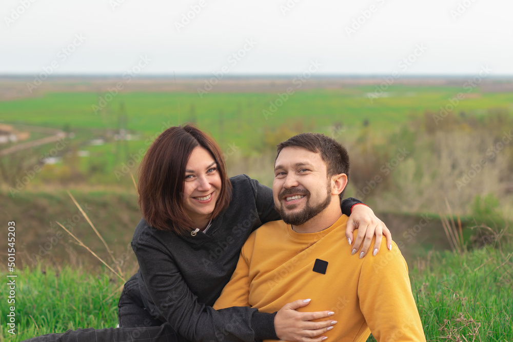 Young happy couple hugging in the park. they look at the camera and smile